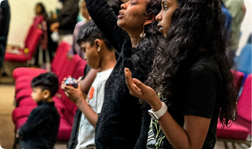 Members of the congregation standing together in worship with hands raised